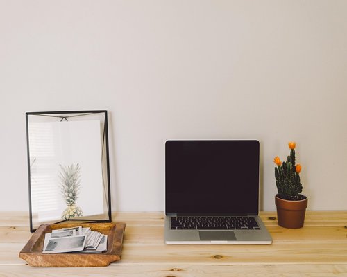 Modern office desk setup in Mexico City with notebooks, a laptop and plants