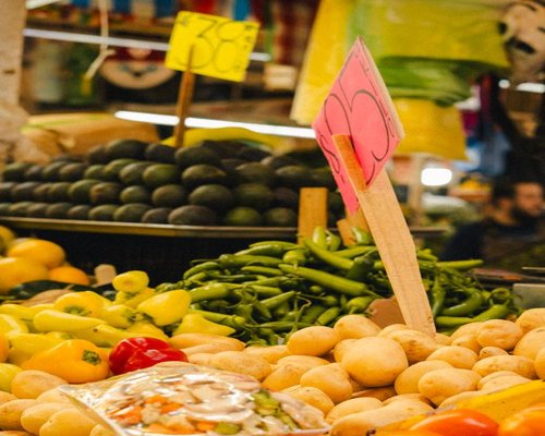 A colorful local Mexican market stall with fresh vegetables like nopales, tomatoes, and avocados